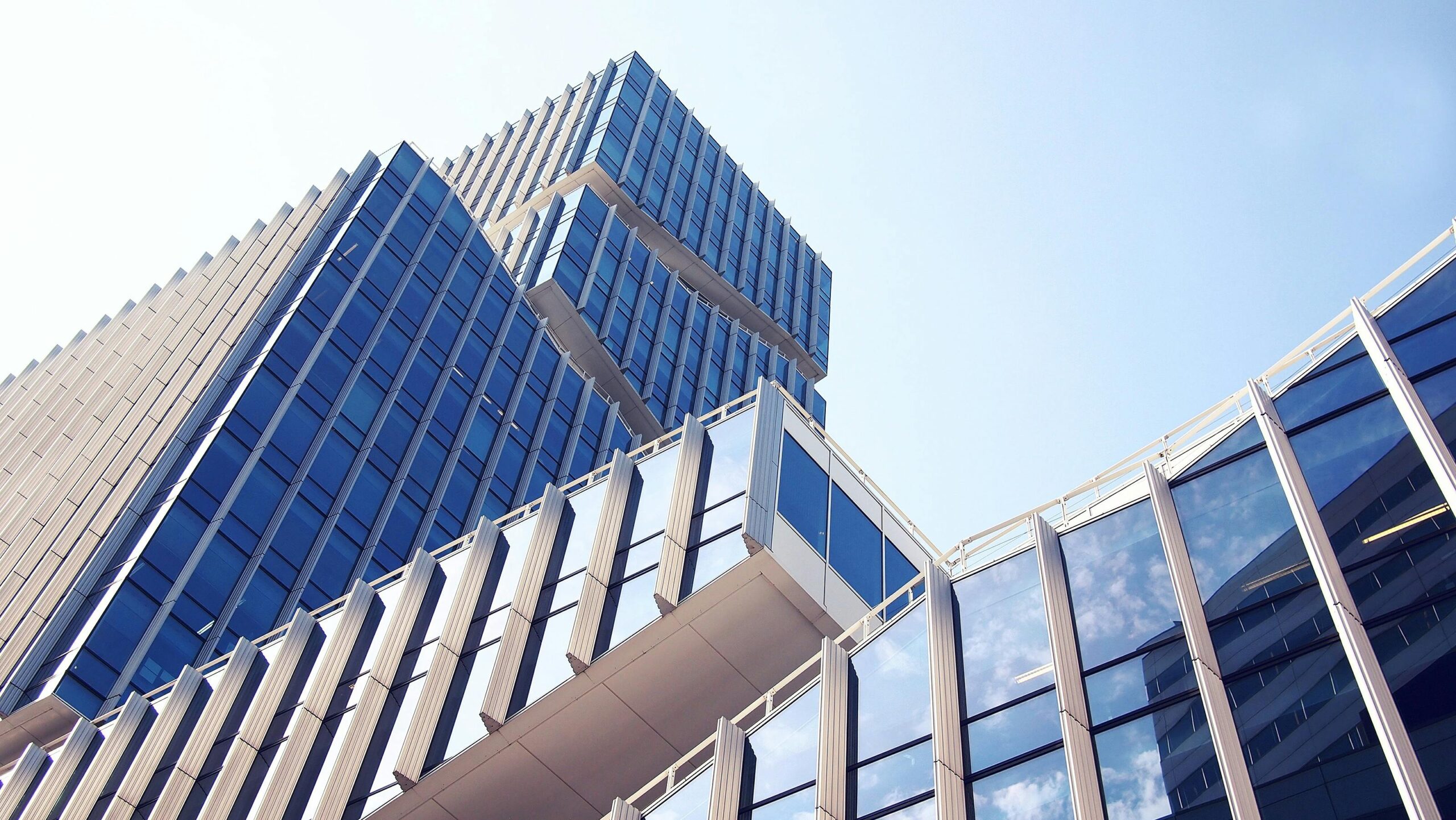 Low-angle shot of a modern skyscraper with reflective glass design under a clear blue sky.